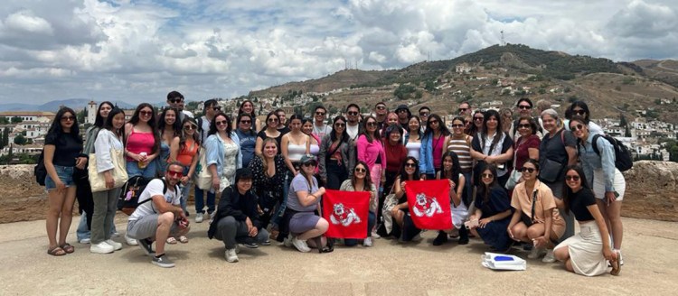 A group takes a photo together in Spain. A mountain can be seen in the background.
