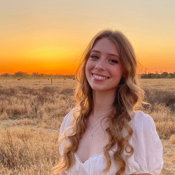 Devynn Brown stands in front of a golden field of grass at sunset.