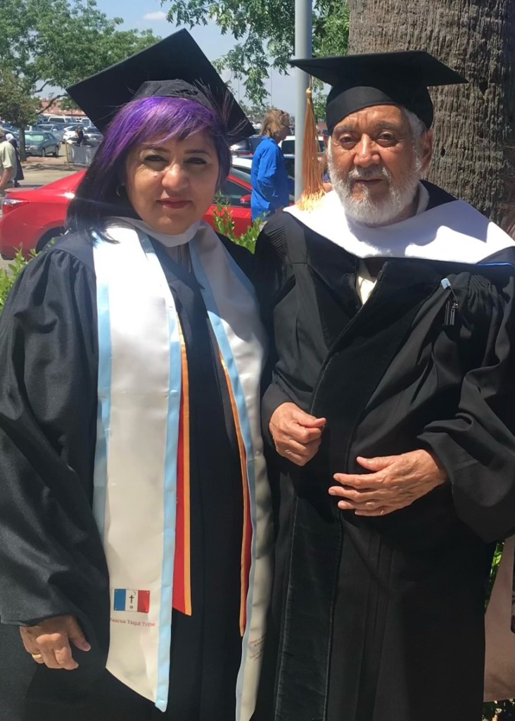 Pam Flores stands with Ernesto Palomino at her M.A. graduation. Palomino came out of retirement to serve on her Master's thesis committee. An artist herself, Pam served as the personal assistant to Palomino in his later years.