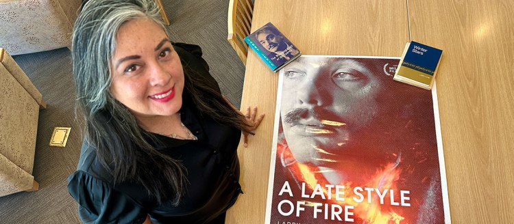 Marisol Baca wiith a poster and books of Larry Levis.