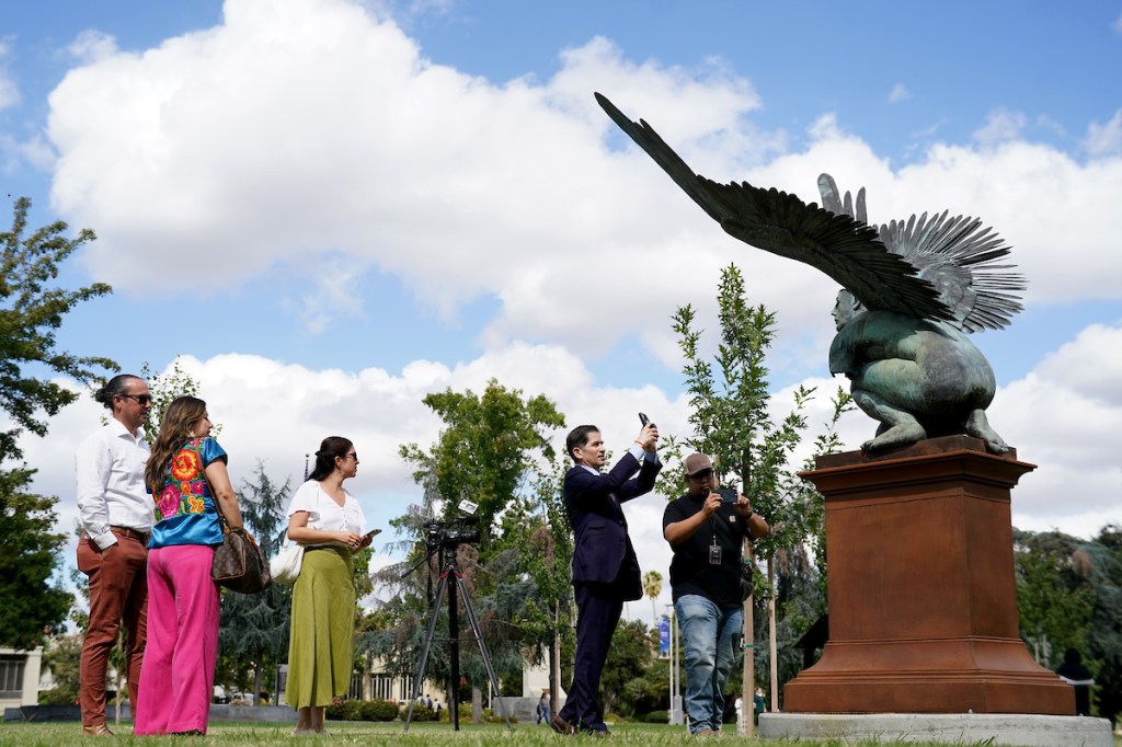 Fresno State President Saúl Jiménez-Sandoval takes a photo of the El Tiempo sculpture.