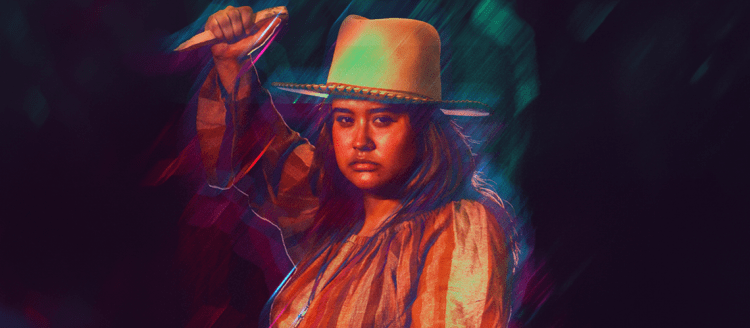 Girl in a cowbow hat holds a knife up as it to stab.