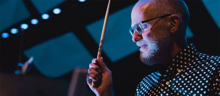 Terry Longshore holds a drumstick and is wearing a dark pokadot shirt.