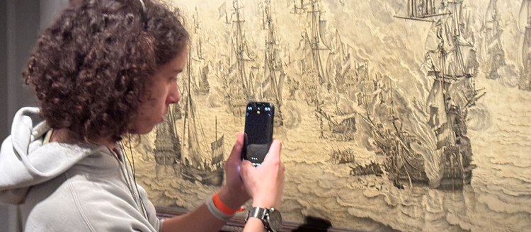 Fresno State student takes a photo of museum artwork on his phone.