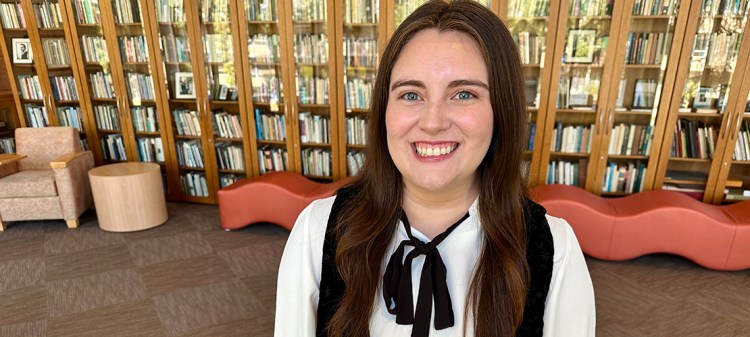 Kayla Mendoza in front of a large bookshelf.