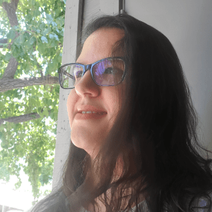 Lena Mubsutina next to a window with a tree