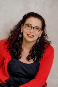 Donna Barba Higuera in a red sweater and dark blue shirt