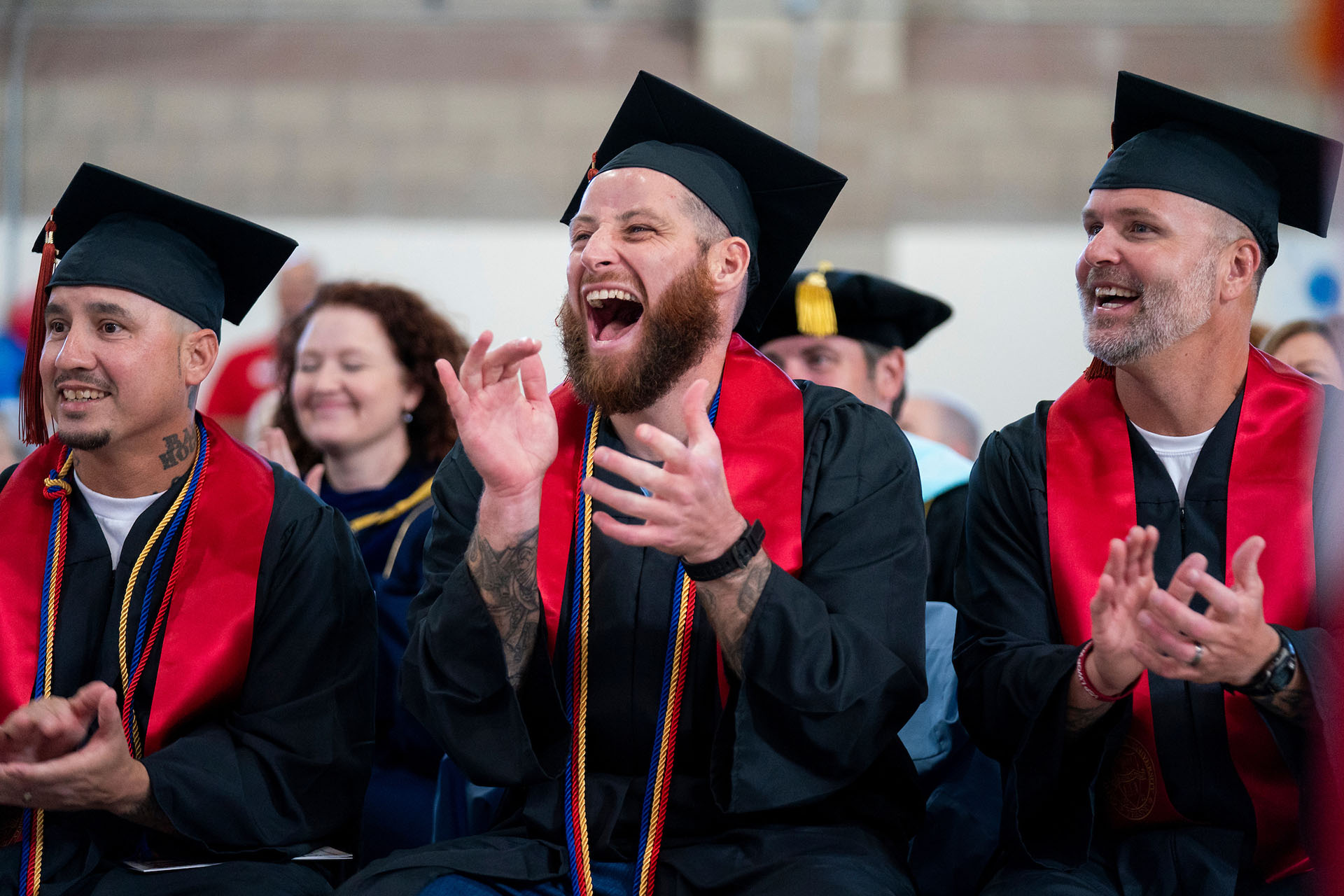 Graduates laugh and clap during commencement ceremony.