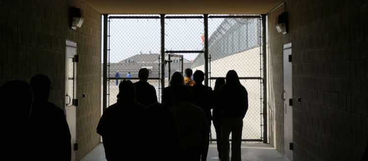 Fresno State debate students enter the prison yard through a dark tunnel with chainlink gate.