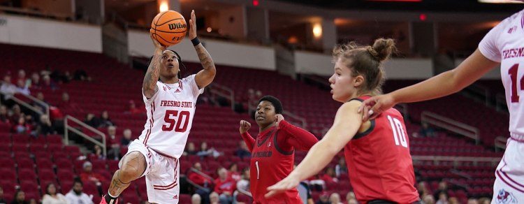 Fresno State women's basketball player performs a jumpshot as two defenders close in on her.