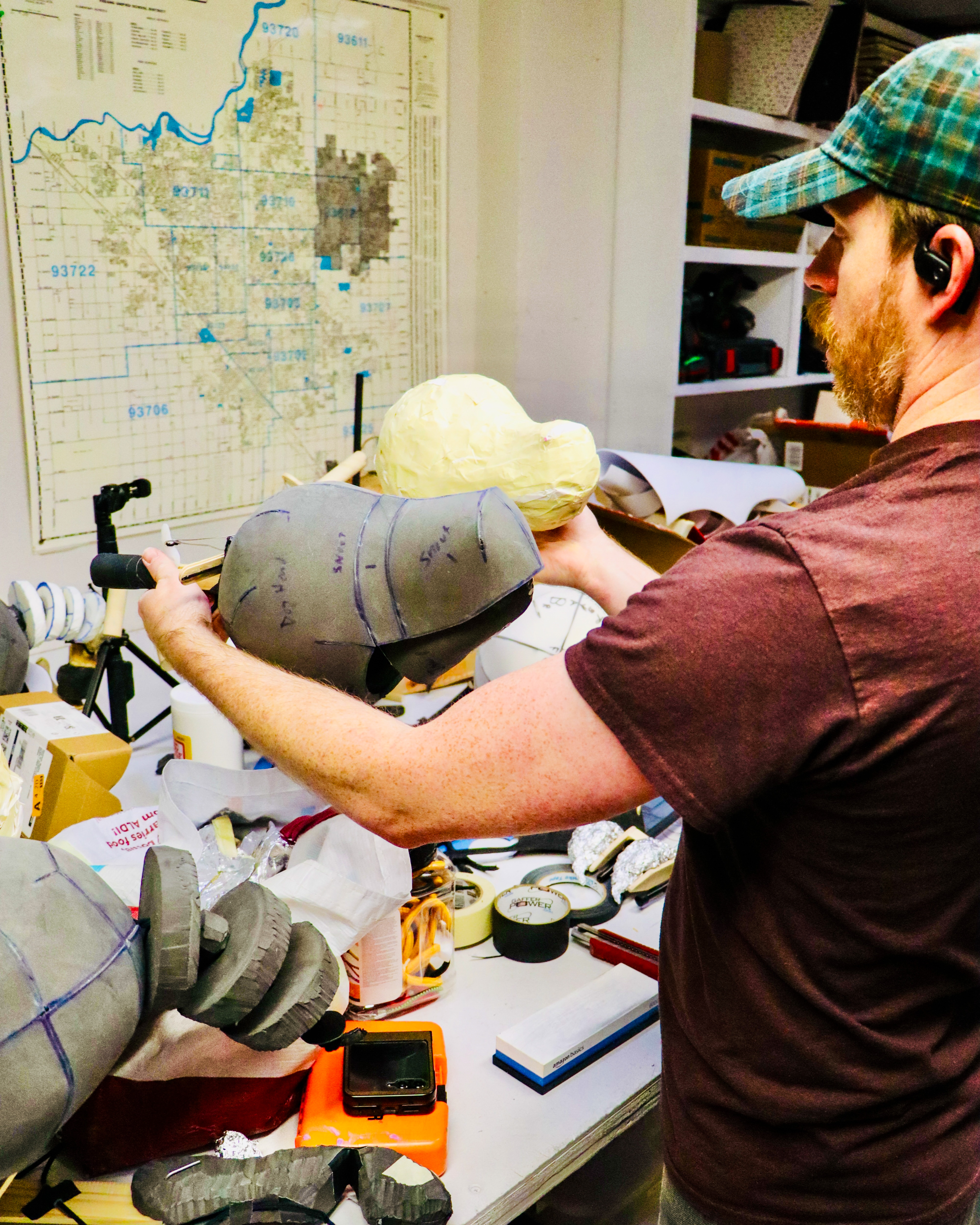 Alumnus Matt McGee holds the structure of a dog's head for a puppet at a workbench.