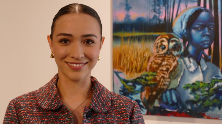 Andrea Espindola Mendoza stands in front of a piece of art in the Dean's Gallery.