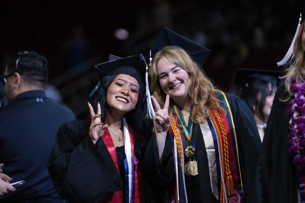 Two grads throw peace signs.
