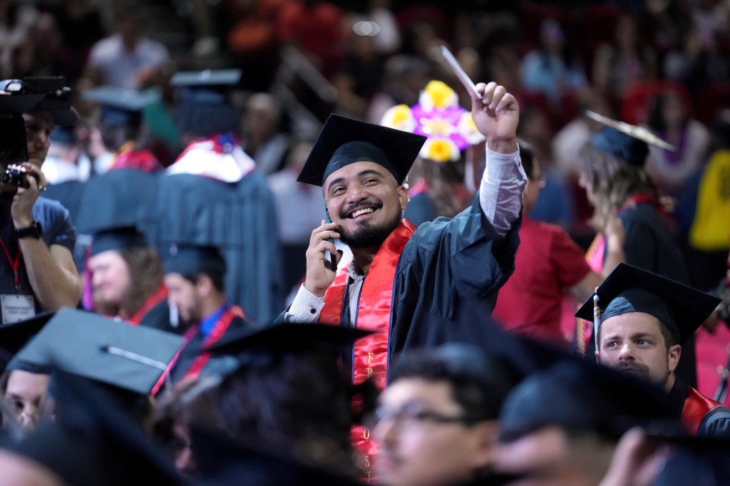 Grad stands while on the phone, connecting with someone in the audience.