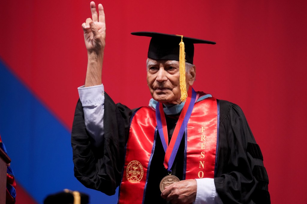 Dr. Kapoor give the peace sign with two fingers.