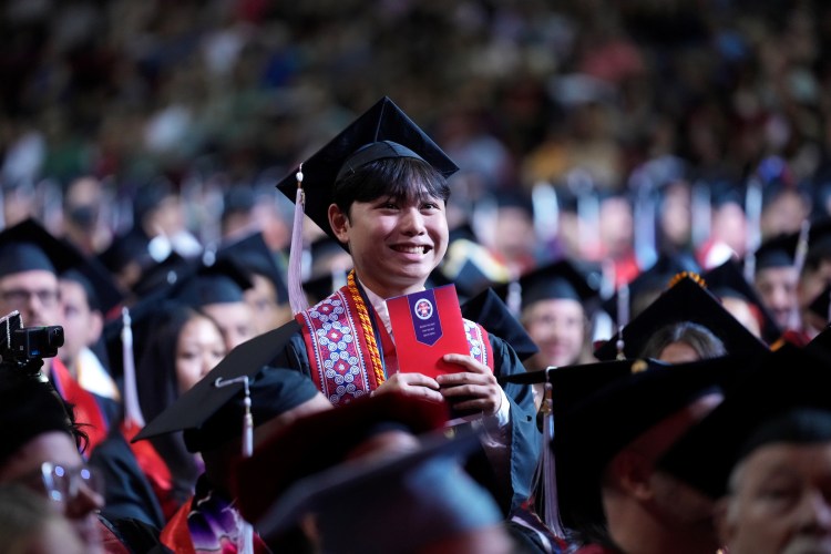 Dean's Medalist Joshua Lor stands amidst sitting graduates as he is honored for his achievement.