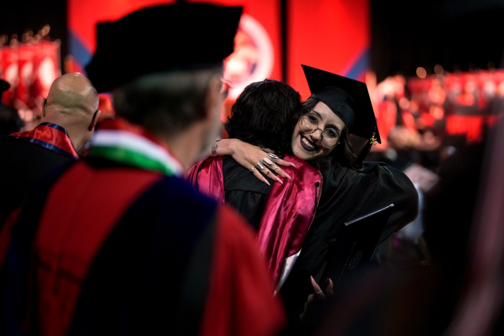 A graduate hugs a faculty member after receiving her diploma.