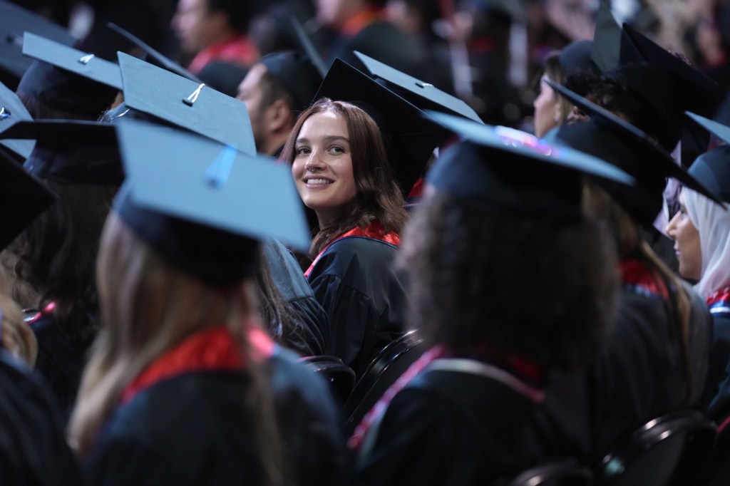 With all the graduates facing forward in their grad caps, one looks back.