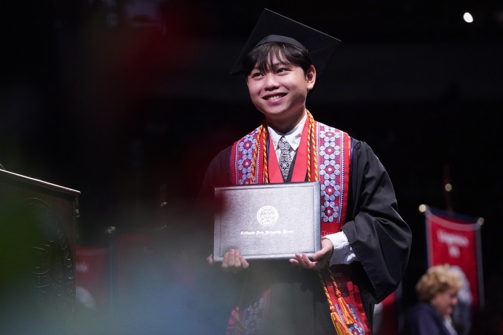 College of Arts and Humanities undergraduate Dean's Medalist Joshua Lor crosses the stage and holds his diploma.