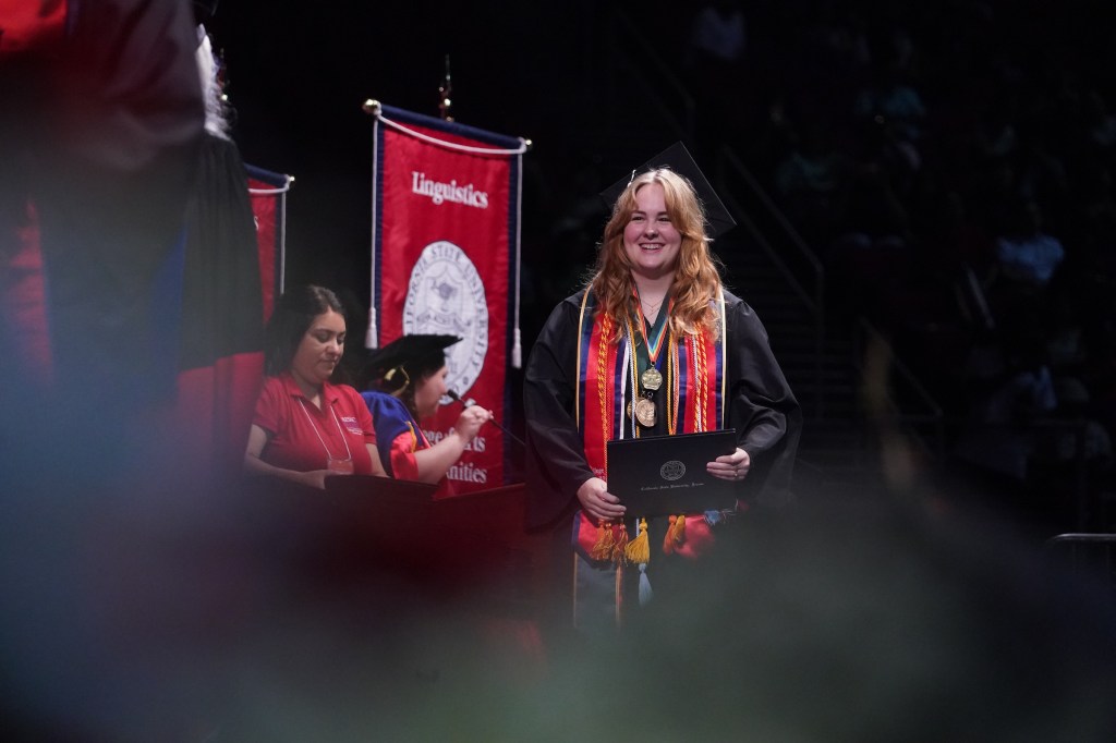 A grad walks across the stage during commencement ceremony.