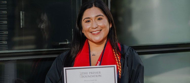 Shakira Delgado in her graduation regalia holds her 2025 Presser Foundation Award