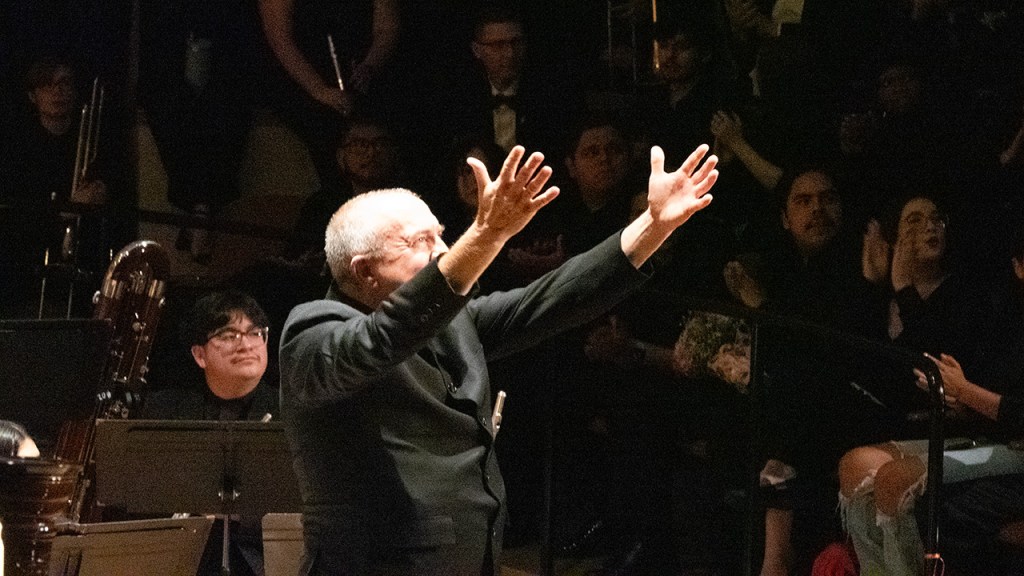 Dr. Gary Gilroy raises his hands toward the audience.